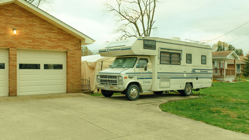 An RV parked outside a residential home, showcasing the distinction between installing solar panels on stationary homes versus mobile RVs.