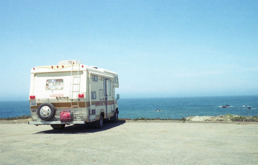 An RV parked near the ocean under a clear sky, highlighting the feasibility of adapting home rooftop solar panels for RV use.