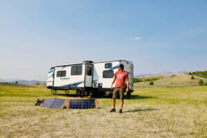 An RV equipped with portable solar panels set up on the ground, illustrating the possibility of adapting solar panel systems for RV use.