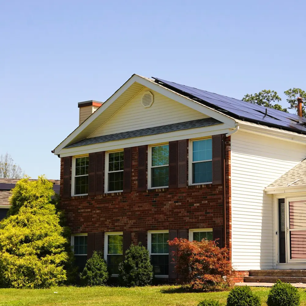 brick facade on home during sunset showing solar panels on roof white siding