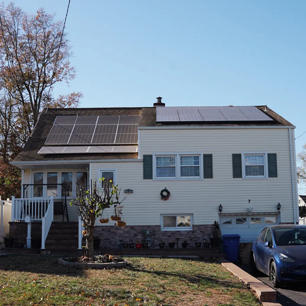 home with yellow siding and solar panels installed wide shot