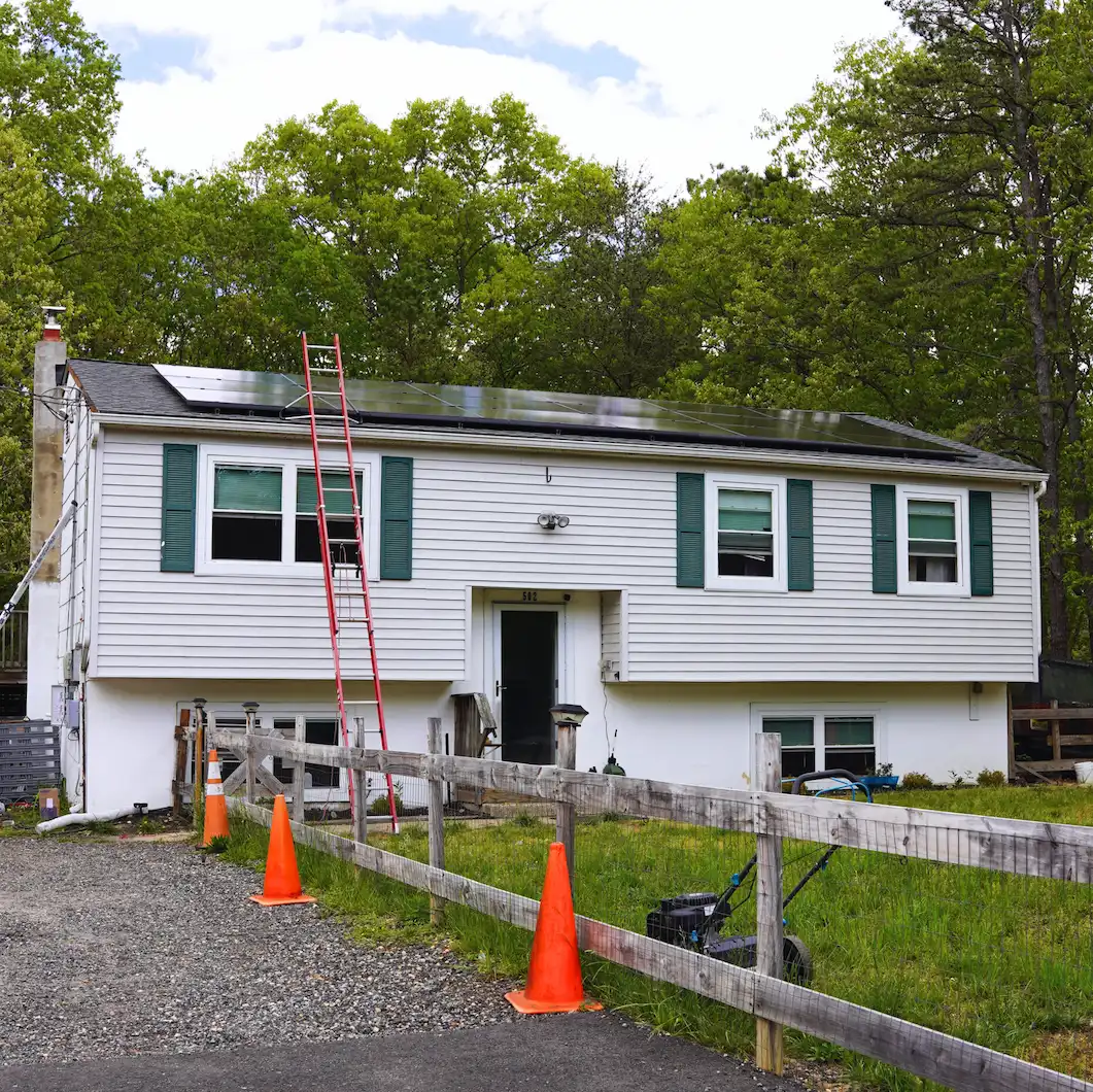 ranch style home with new solar panels on roof, green shutters