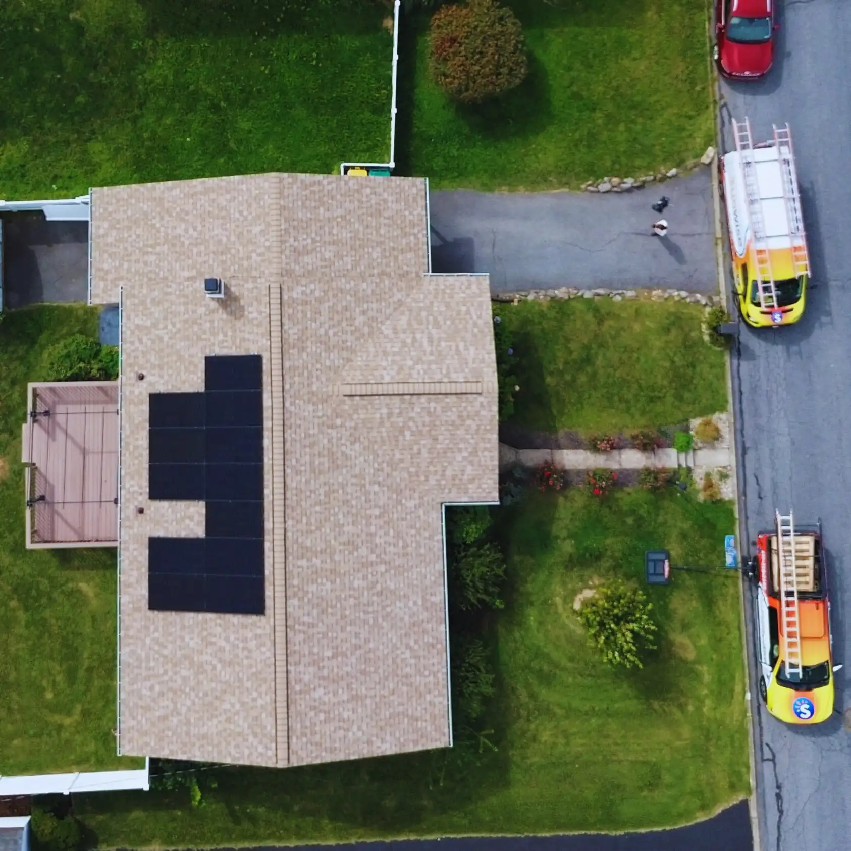 drone shot birds eye view of ranch home with patio and small solar panel system newly installed on beige roof