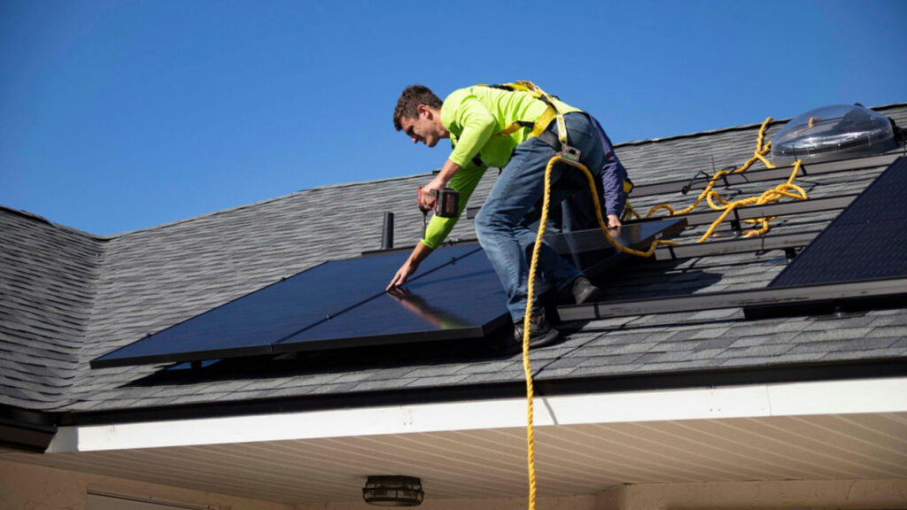 Technician installing monocrystalline solar panels on a roof