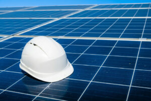 A solar-powered heater with a single glass panel shown with a white hard hat resting on the solar panel surface.