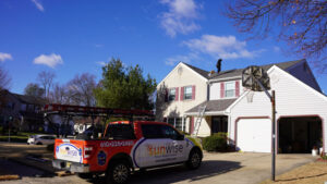 Sunwise Energy truck parked outside a house while technicians fix a flexible solar panel on the roof.