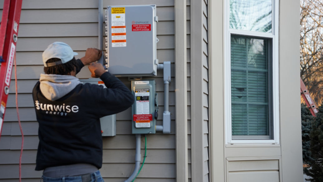 SunWise technician installing solar battery equipment for a 12V solar battery charger system