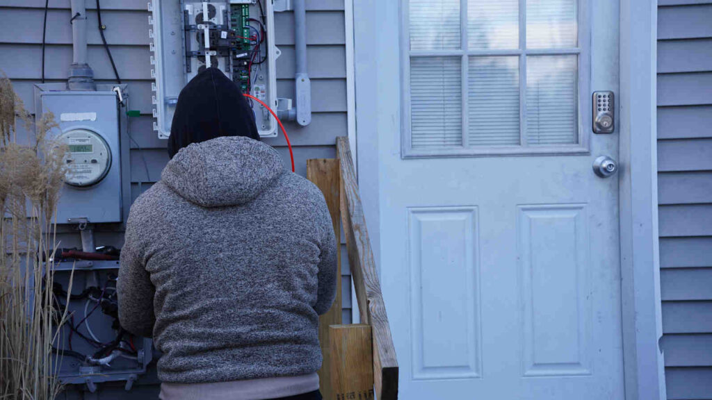 Technician inspecting an outdoor electrical panel during a home energy audit to assess energy usage and improve household efficiency.